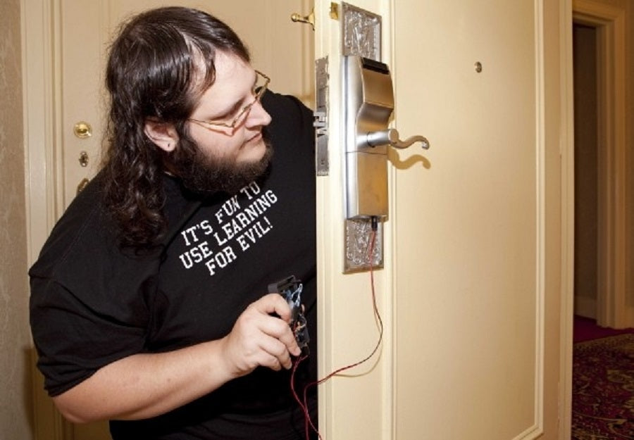 picture of a hacker hacking an Onity hotel door lock with a handheld device