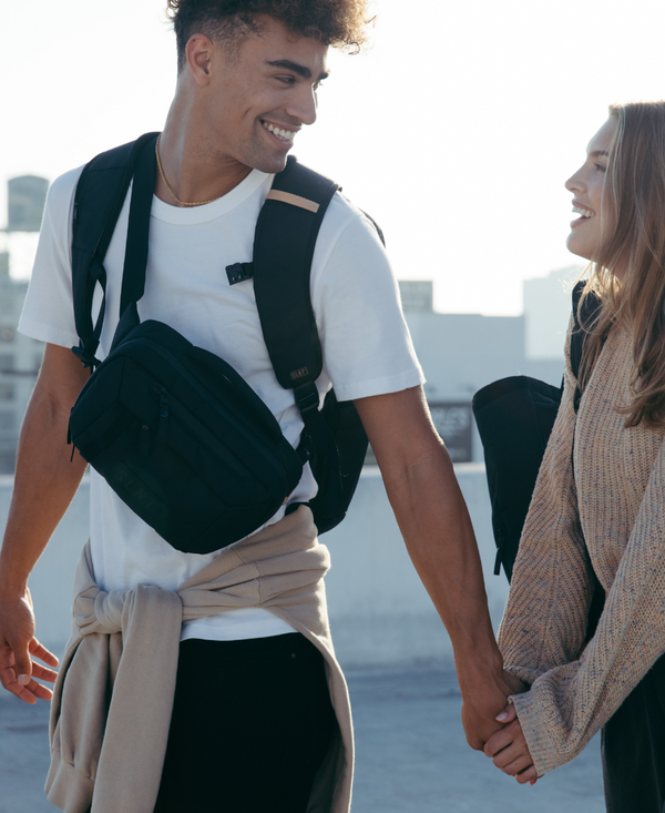 Man and women holding hands wearing SLNT Faraday bags