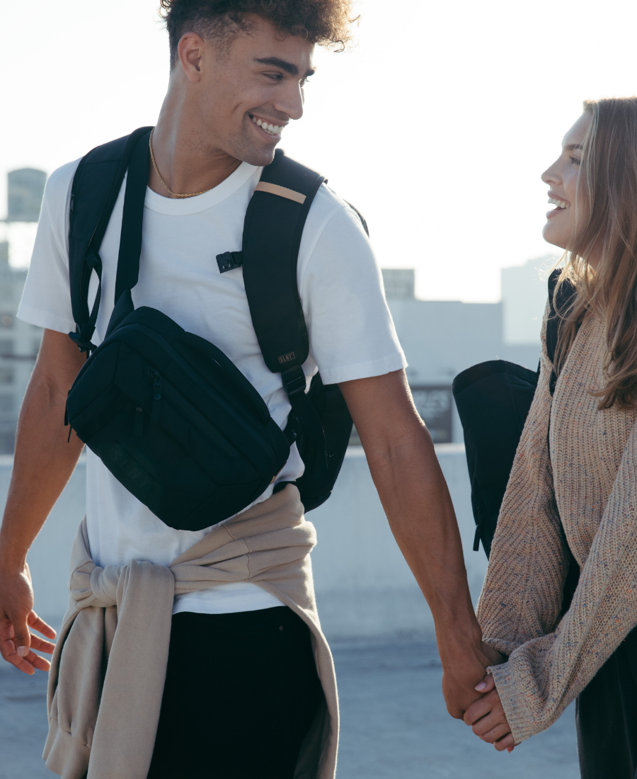 Man and women holding hands wearing SLNT Faraday bags