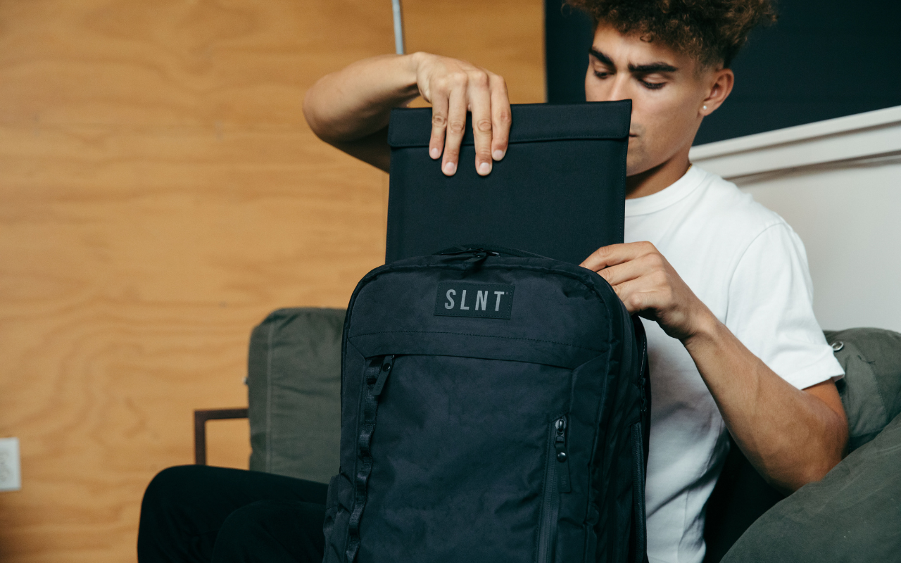 Man putting Faraday sleeve into SLNT backpack